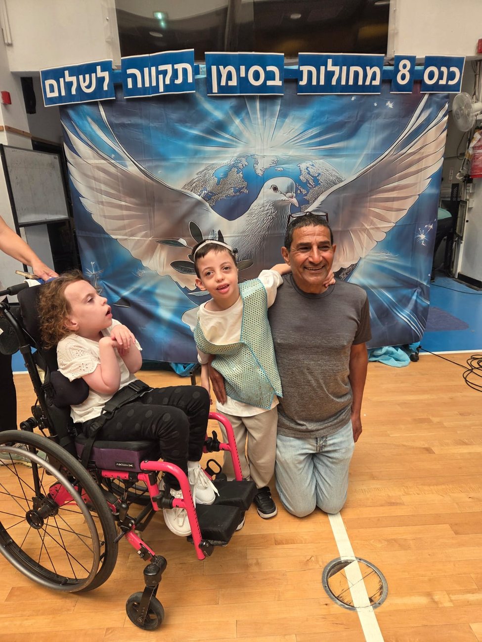 Mr. Eyal Ozeri with conference students in front of a hope-for-peace banner